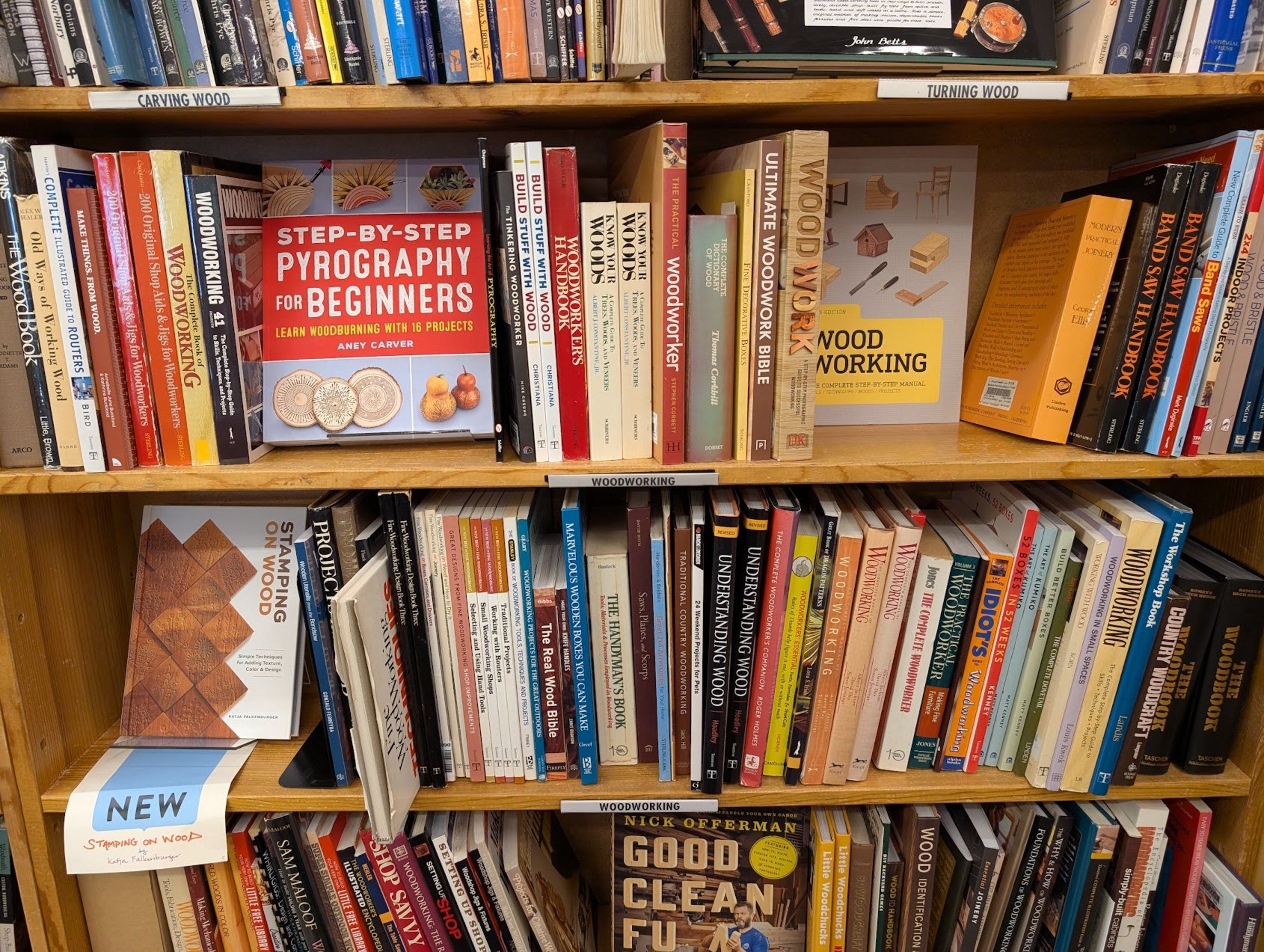 Bookshelves packed with woodworking books, with
    shelf labels for carving wood, turning wood, and woodworking.